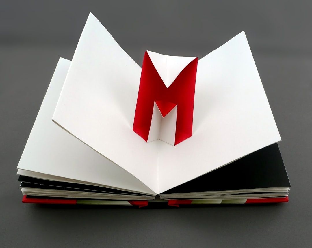 Open artist book with a sculptural red-and-white letterform rising from its pages